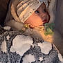 baby, baby_accessories, blanket, bow, child, clothing, cute, face, fluffy, gaze, headwear, indoors, infant, pacifier, patterned_blanket, peaceful, portrait, soft_lighting, turban, warm_colors