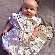 Emy participe au concours pour gagner de l'argent avec cette photo : 3_months, baby, blanket, bow_pattern, child, cute, dress, flower, happy, indoors, infant, lying_down, milestone, pattern, person, portrait, sign, skin, smiling, white_dress