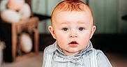 Josiah is registered to the contest to win money with this photo: baby, child, boy, blue_clothing, bow_tie, suspenders, fluffy_rug, indoor, portrait, curious_expression, decorations, carrot_decor, rustic_background, soft_lighting, seated, cute, young_child, face, head, photography