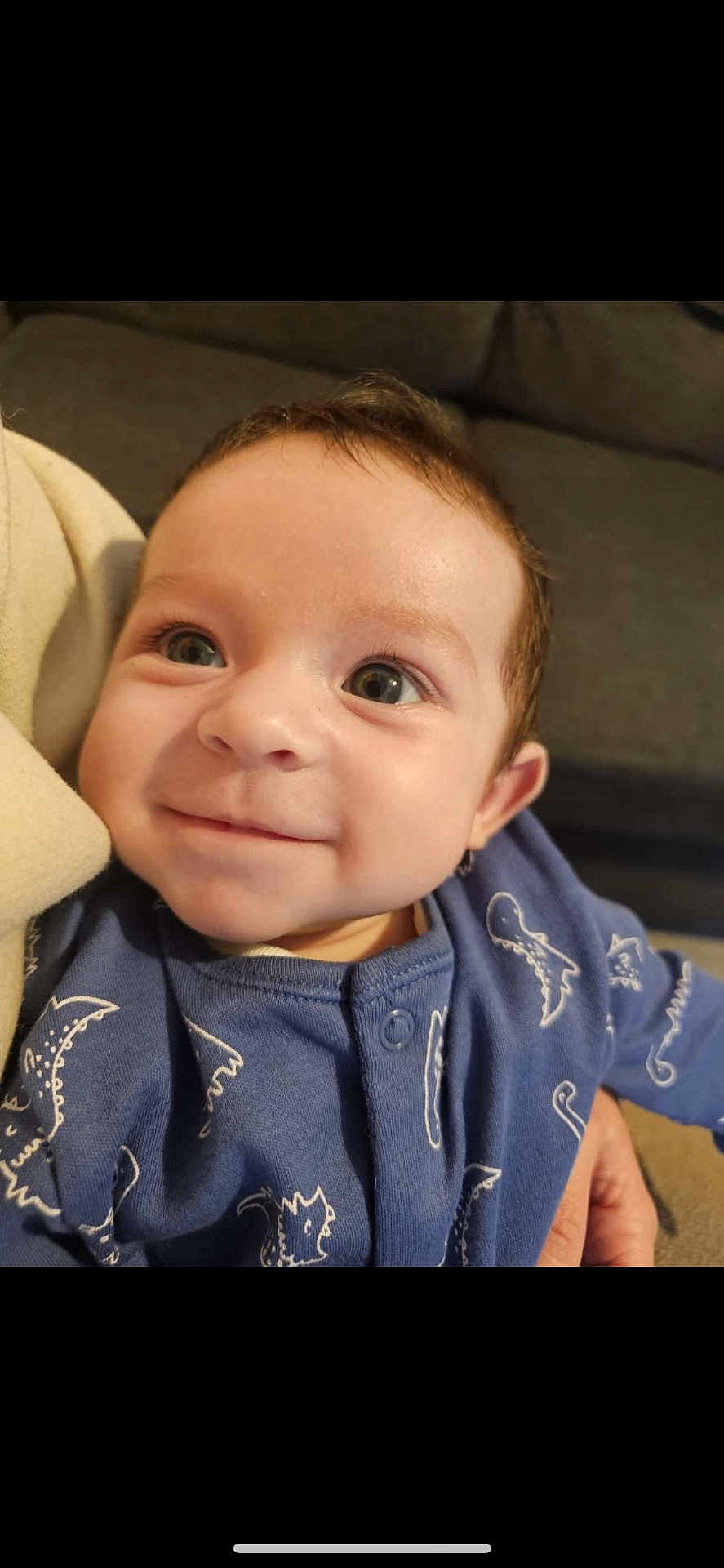 Roman joined the competition — help win amazing prizes! baby, child, smiling, face, blue_clothing, dinosaur_print, indoor, portrait, cute, young, infant, person, happy, eyes, cozy, couch, closeup, skin, hair, expression