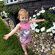 River joined the competition — help win amazing prizes! barefoot, child, cute, flower_bed, flowers, garden, grass, greenery, minnie_mouse, nature, outdoor, person, pink_dress, plants, rocks, smiling, stone_wall, summer, toddler, window