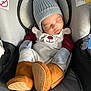 baby, sleeping, car_seat, knit_hat, mittens, boots, infant, cozy, winter_clothing, cute, child, apparel, padded_seat, safety_warnings, resting, portrait, indoor, soft_lighting, closed_eyes, newborn