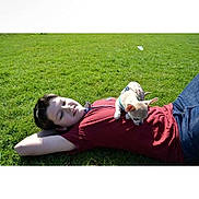 Booboo is registered to the contest to win money with this photo: person, dog, grass, outdoor, lying_down, pet, casual_clothing, sunny, relaxation, small_dog, chihuahua, greenery, nature, happy, companion, daytime, leisure, animal, friendship, resting