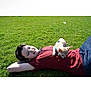person, dog, grass, outdoor, lying_down, pet, casual_clothing, sunny, relaxation, small_dog, chihuahua, greenery, nature, happy, companion, daytime, leisure, animal, friendship, resting