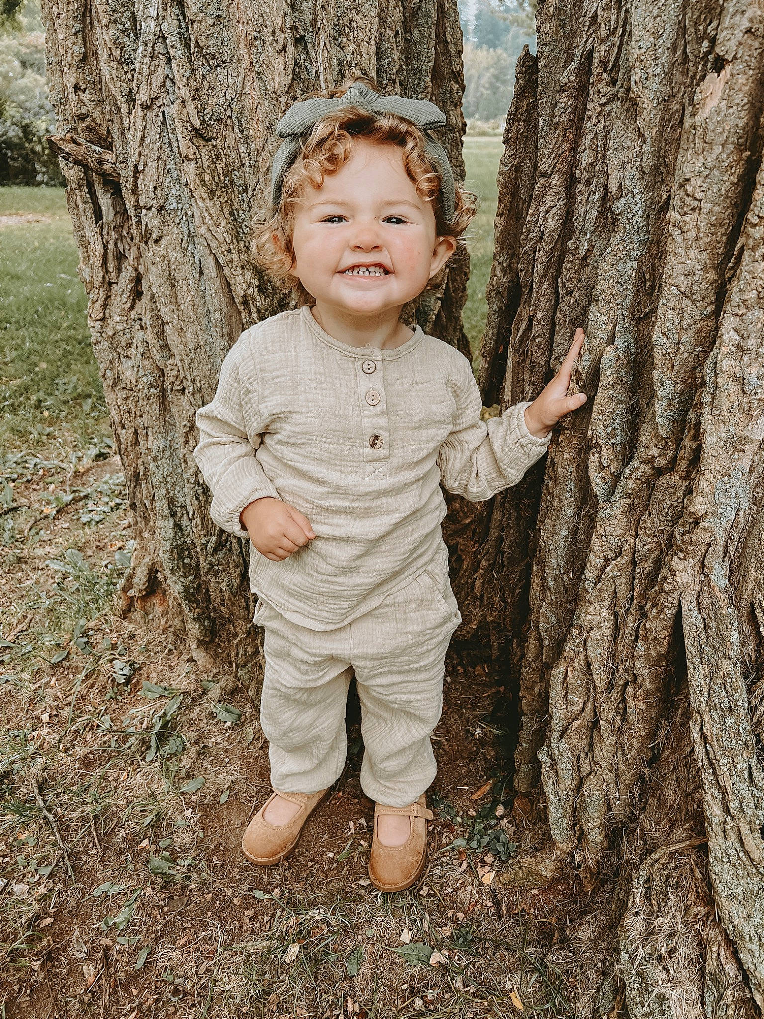 Ana is registered to the contest to win money with this photo: baby_toddler_clothing, child, eye, face, forest, gesture, grass, happy, iris, joy, people_in_nature, person, plant, sleeve, smile, standing, toddler, tree, trunk, wood