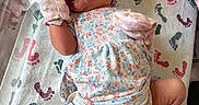 Olivia joined the competition — help win amazing prizes! baby, newborn, infant, mittens, headband, floral_outfit, hospital_blanket, footprint_pattern, lying_down, smiling, cute, small_hands, small_feet, bed, pink, white, blue, green, soft_lighting, portrait