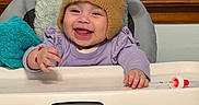 Sahara joined the competition — help win amazing prizes! baby, baby_toys, bear_ears, child, cushion, cute, feeding_chair, happy, high_chair, home, indoor, infant, knit_hat, person, portrait, purple_clothing, smiling, socks, warm_clothing, window