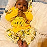 baby, infant, child, yellow_clothing, headband, cute, lying_down, blanket, soft_texture, indoors, cozy, hand_on_mouth, bright_colors, bee_pattern, foot, sleepwear, portrait, young_child, comfortable, closeup