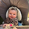 baby, child, smile, leopard_print, headband, cushion, chair, toy, hand, face, outdoor, sunlight, happy, infant, apparel, person, portrait, rosy_cheeks, seat, cozy