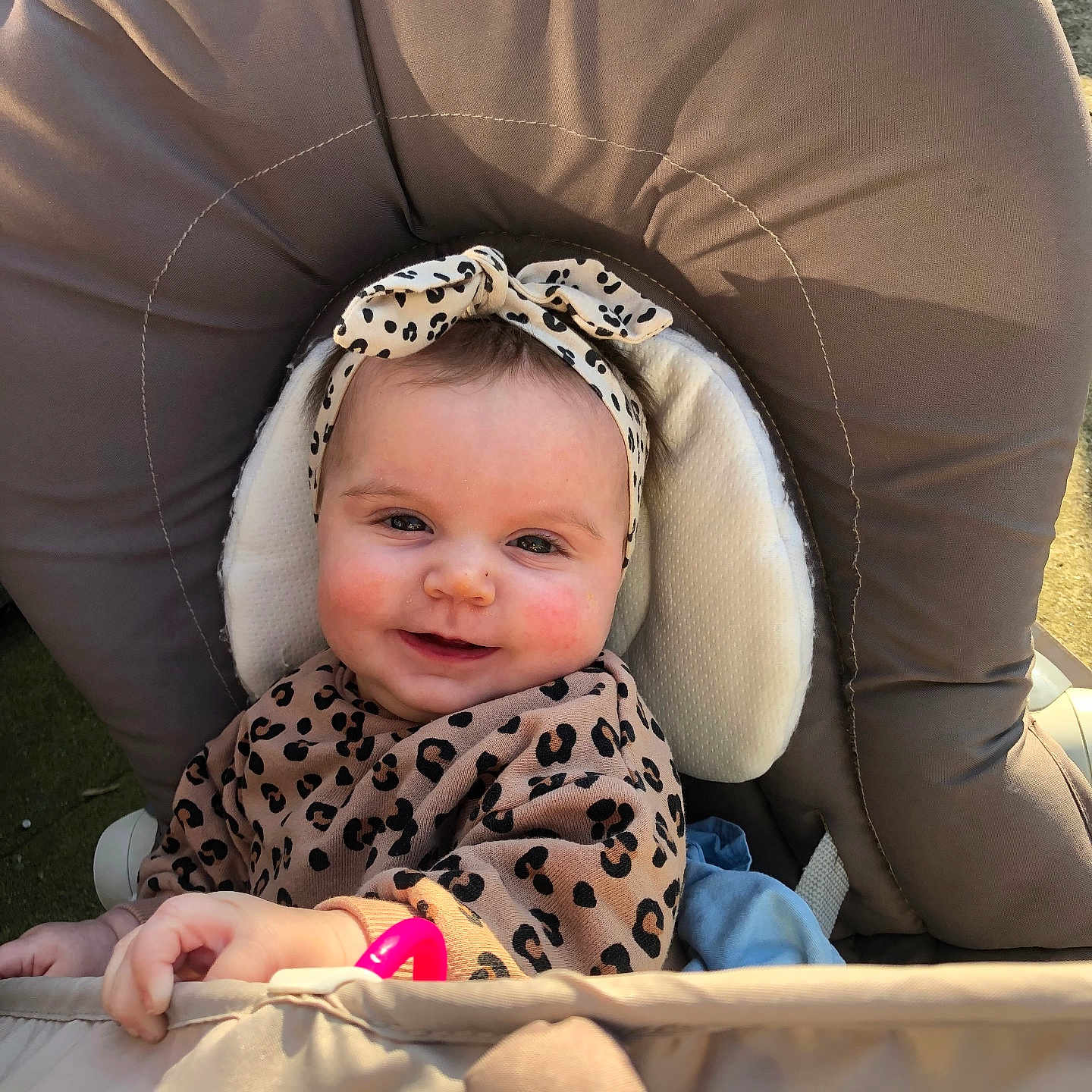Ameliane is registered to the contest to win money with this photo: baby, child, smile, leopard_print, headband, cushion, chair, toy, hand, face, outdoor, sunlight, happy, infant, apparel, person, portrait, rosy_cheeks, seat, cozy