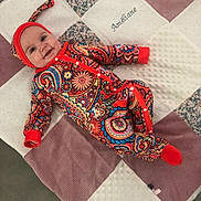 Améliane participe au concours pour gagner de l'argent avec cette photo : baby, bedding, blanket, button_closure, cheeks, colorful_outfit, cotton, eyes, face, footie, happy, headband, infant, lying_down, nursery, paisley, patterned_clothing, portrait, quilt, smiling