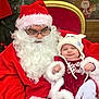 Améliane participe au concours pour gagner de l'argent avec cette photo : baby, santa_claus, christmas, holiday, festive, red_clothing, white_beard, glasses, hat, costume, smiling, chair, decorations, tree, ornaments, indoor, celebration, person, cute, warm_clothing