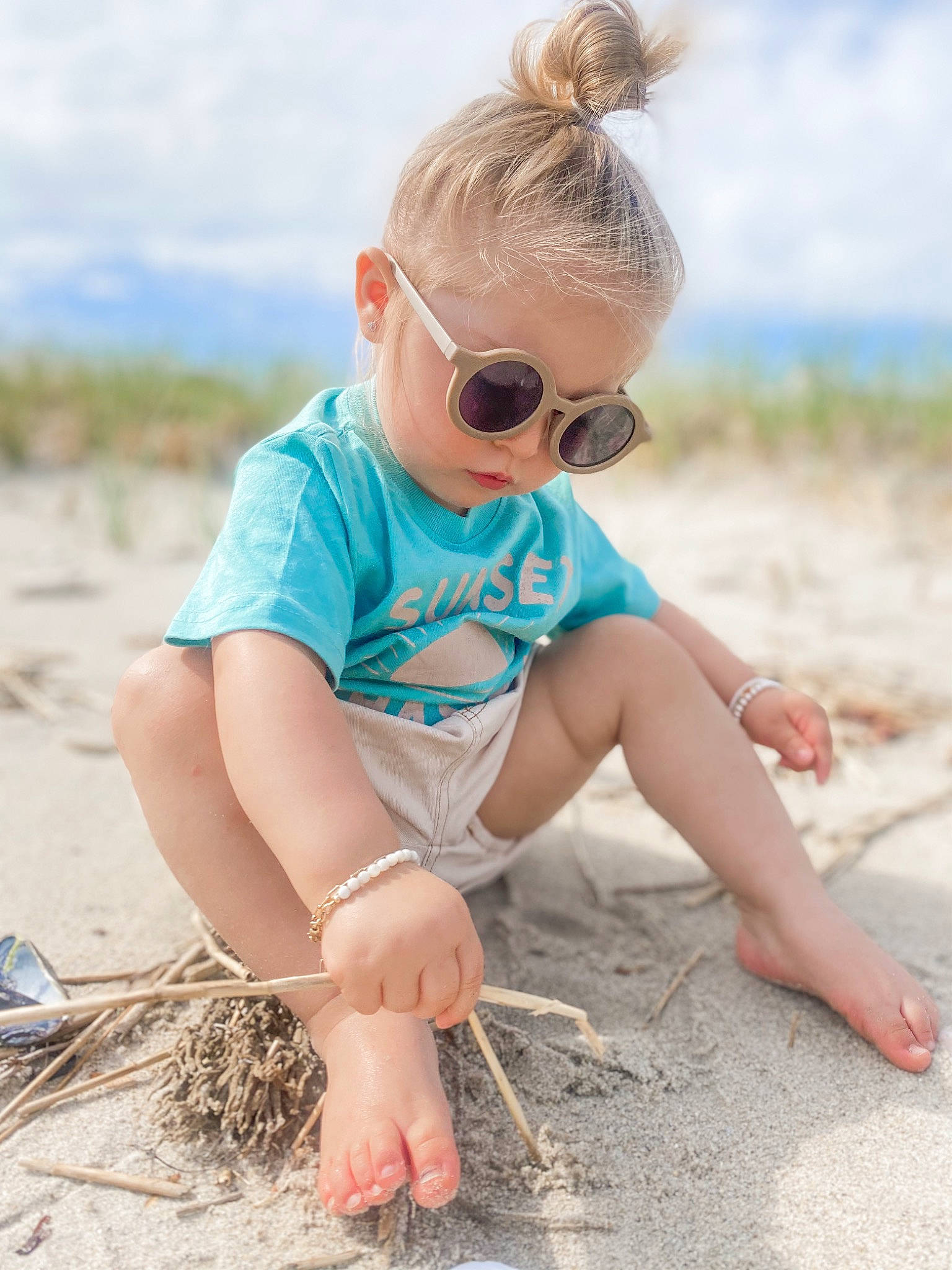 Thea is registered to the contest to win money with this photo: azure, beach, body_of_water, eyewear, fun, glasses, goggles, grass, hair, happy, human_body, leisure, mammal, people_in_nature, person, recreation, sand, shorts, sky, sunglasses