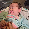 Madilynn is registered to the contest to win money with this photo: baby, smiling, sleepy, blanket, sweater, cushion, indoor, child, face, person, resting, comfort, soft, clothing, hand, head, hair, pink, green, expression