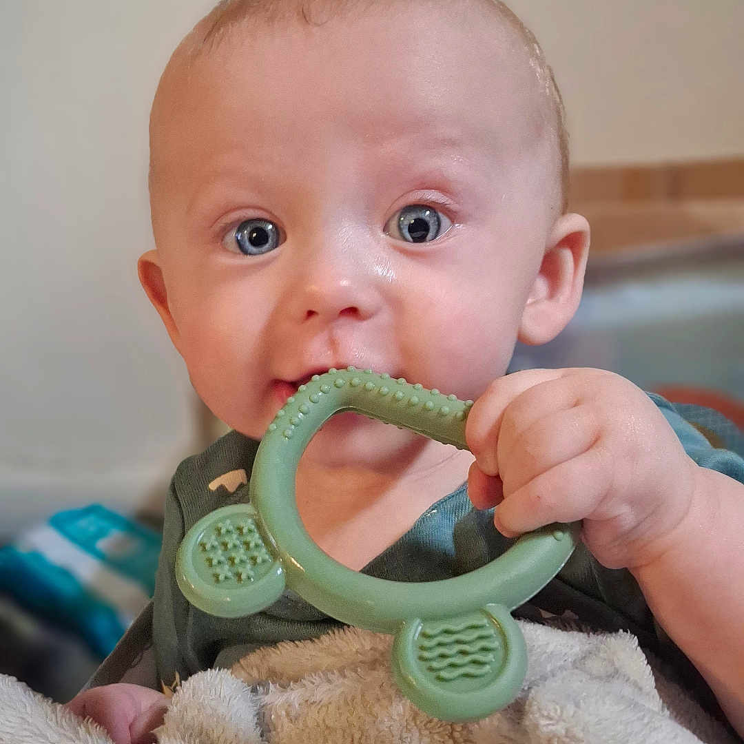 Ashtynn is registered to the contest to win money with this photo: baby, child, teething_toy, blanket, blue_eyes, hand, face, infant, chewing, curious, cute, indoors, soft_light, portrait, close_up, skin, fingertips, young_child, comfort, toddler