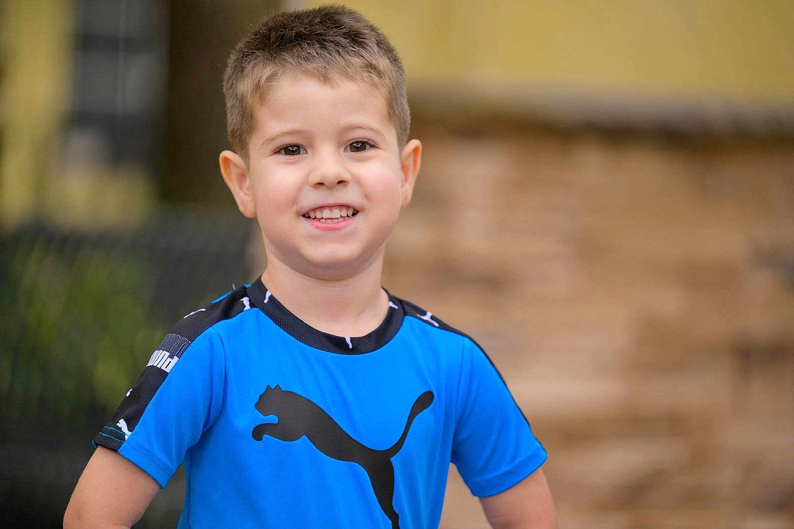 Carlos López joined the competition — help win amazing prizes! child, boy, smile, portrait, blue_shirt, puma_logo, short_hair, teeth, ears, eyes, skin, happy, outdoor, blurred_background, bokeh, sportswear, standing, casual_clothing, person, youth