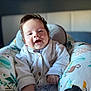 baby, smiling, infant, cardigan, knitwear, baby_seat, animal_pattern, cozy, happy, face, portrait, cute, child, clothing, indoor, soft_light, furniture, sitting, young, person