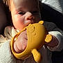 baby, child, teething_toy, yellow, closeup, face, hand, knitted_sweater, soft_light, indoor, curious, cute, infant, skin, portrait, young_child, toy, chewing, warm_light, casual