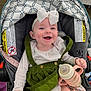 baby, infant, smiling, stroller, bottle, bow, white_bow, green_dress, baby_clothes, happy, child, cute, seated, indoor, person, holding, feeding_bottle, pink, fabric, button