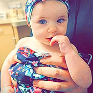 Sage is registered to the contest to win money with this photo: baby, child, blue_eyes, headwrap, floral_pattern, dress, hand, finger_in_mouth, indoor, kitchen, soft_focus, cute, person, infant, holding, skin, portrait, young_child, colorful, closeup