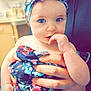 baby, child, blue_eyes, headwrap, floral_pattern, dress, hand, finger_in_mouth, indoor, kitchen, soft_focus, cute, person, infant, holding, skin, portrait, young_child, colorful, closeup
