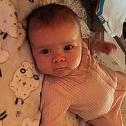 Lilly is registered to the contest to win money with this photo: baby, infant, blanket, sheep_pattern, pink_clothing, lying_down, carpet, wooden_furniture, indoors, cute, face, child, warm_lighting, soft_texture, floor, home, cozy, portrait, expression, newborn