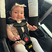 Evie is registered to the contest to win money with this photo: baby, car_interior, car_seat, child, clothing, cute, floral_pattern, happy, headband, infant, legs, person, portrait, safety, seatbelt, sitting, smile, straps, white_socks, young_child