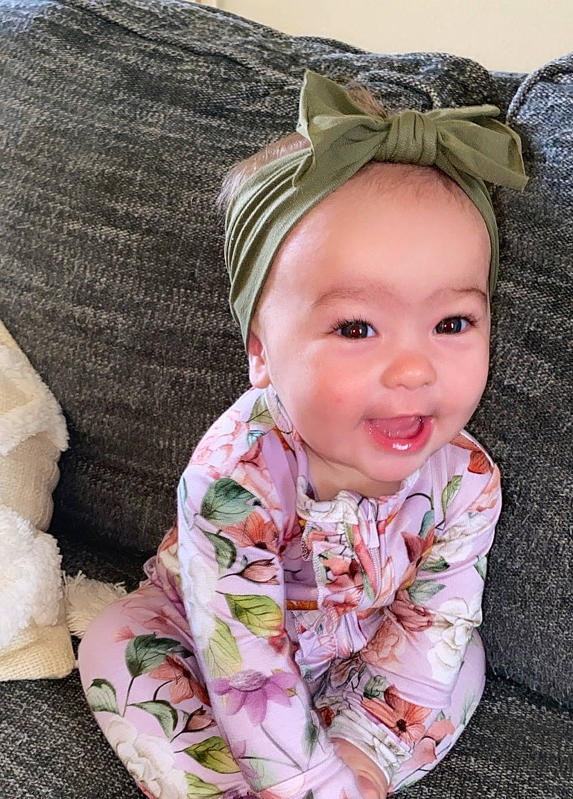 Collins is registered to the contest to win money with this photo: baby, baby_toddler_clothing, cheek, comfort, eye, face, grass, happy, head, iris, linens, lip, outerwear, pattern, person, pink, skin, sleeve, smile, textile