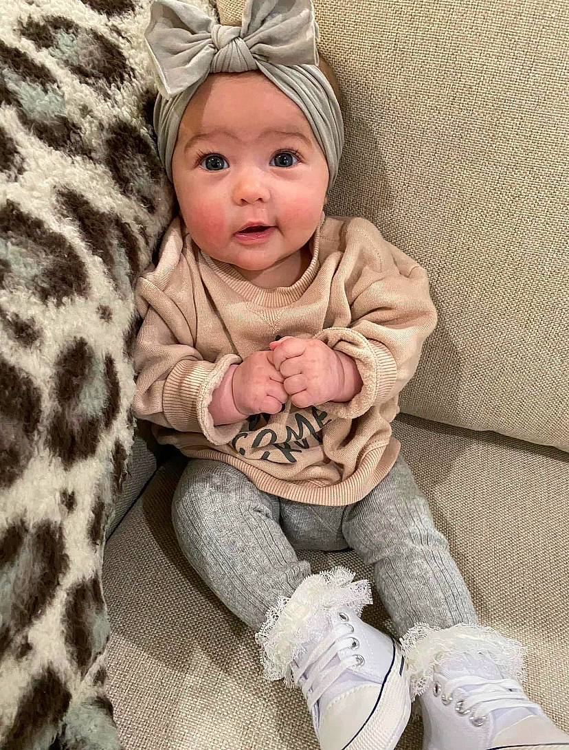 Collins is registered to the contest to win money with this photo: baby, baby_toddler_clothing, beauty, cap, child, comfort, costume_hat, headwear, human_body, linens, organ, pattern, person, skin, sleeve, smile, sneakers, sock, textile, toddler