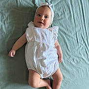 Lyloo a rejoint le concours — aidez-le/la à gagner de superbes lots ! baby, infant, smiling, headband, romper, clothing, lying_down, blanket, soft_texture, cute, child, person, skin, legs, arms, face, happy, indoors, portrait, playful