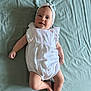 baby, infant, smiling, headband, romper, clothing, lying_down, blanket, soft_texture, cute, child, person, skin, legs, arms, face, happy, indoors, portrait, playful