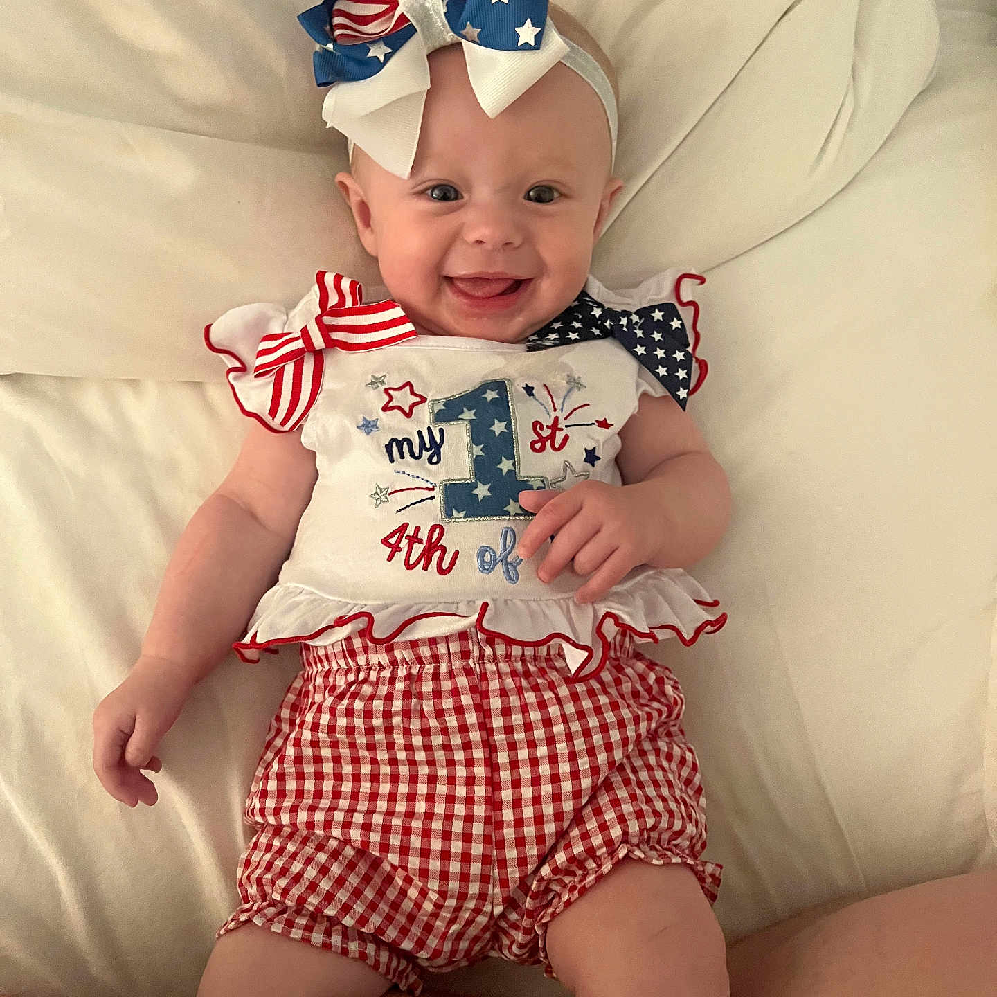 Tilly joined the competition — help win amazing prizes! baby, infant, smiling, red_white_blue, bow, headband, clothing, cute, celebration, holiday, lying_down, white_background, happy, cheerful, portrait, child, people, one_year_old, patterned_clothing, festive
