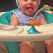Tilly is registered to the contest to win money with this photo: baby, child, blue_bow, smiling, tongue_out, baby_seat, toy, teal, headband, happy, infant, cute, indoor, playful, person, clothing, sitting, face, young_child, baby_toys
