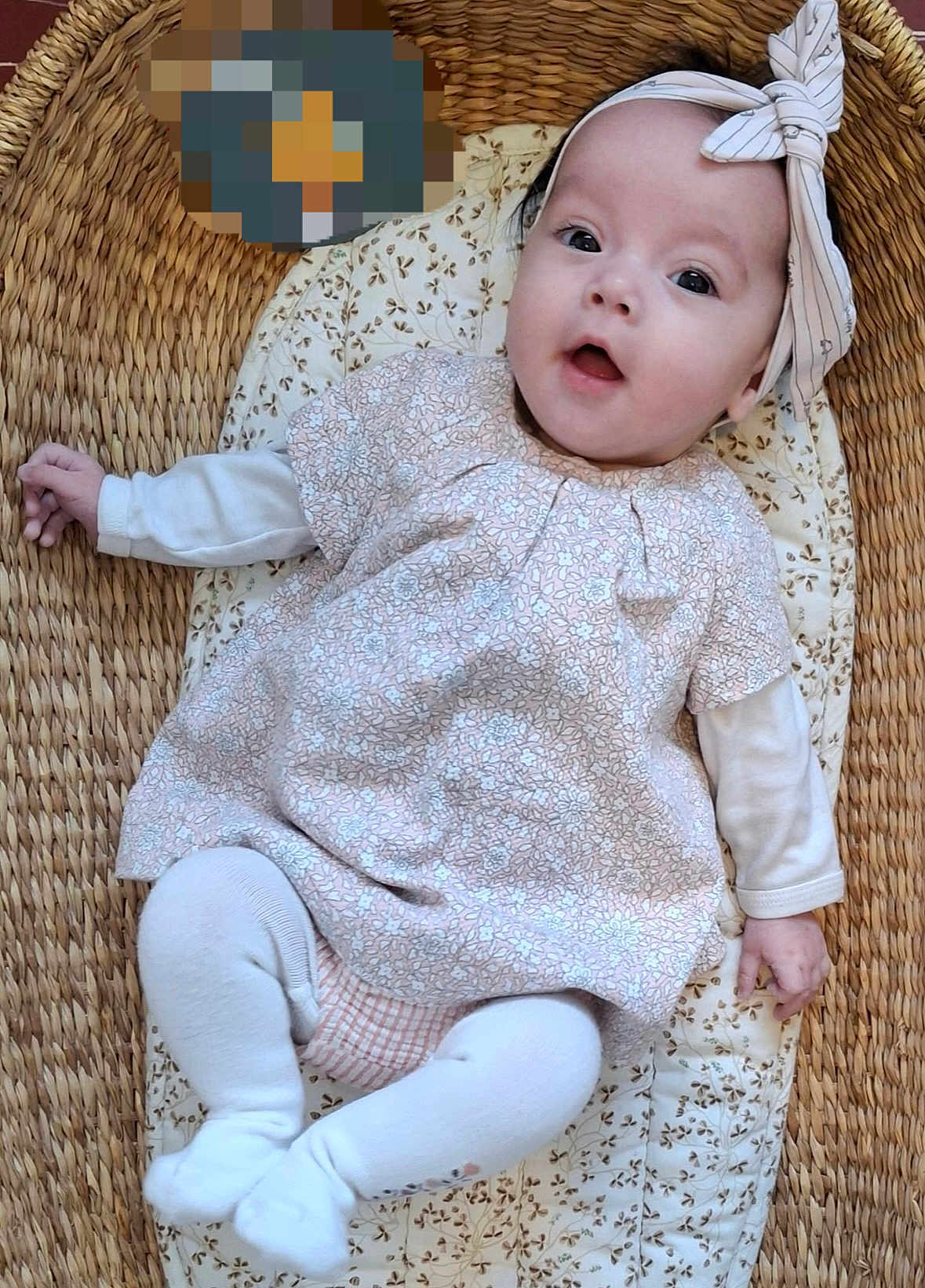 Lila participe au concours pour gagner de l'argent avec cette photo : baby, infant, child, headband, bow, dress, floral_pattern, basket, woven, cushion, lying_down, cute, cozy, indoors, white_tights, clothing, portrait, face, expression, person