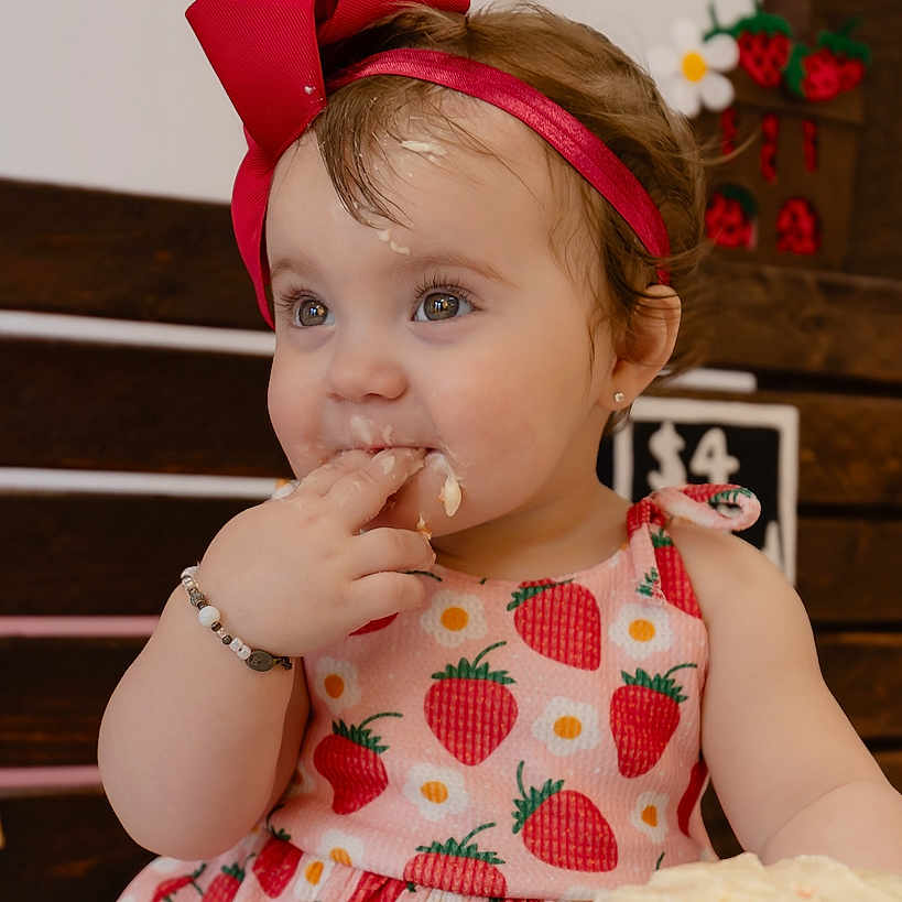 Adalynn is registered to the contest to win money with this photo: accessories, baby, bodypart, bracelet, cake, clothing, cream, dessert, dress, eating, face, finger, food, hand, head, icecream, icing, jewelry, person, sweets