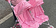 Bonnie-Leigh is registered to the contest to win money with this photo: casual_clothing, child, curly_hair, cute, daylight, double_stroller, footwear, fun, hair_tie, happy, outdoor, pavement, person, pink_jacket, play, sidewalk, small_wheels, smiling, toddler, toy_stroller