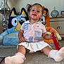Bonnie-Leigh joined the competition — help win amazing prizes! carpet, child, cute, furniture, happy, home_decor, indoor, person, photo_frame, pigtails, playful, plush_toys, shirt, sitting, skirt, smiling, sock, toddler, toy, young_child