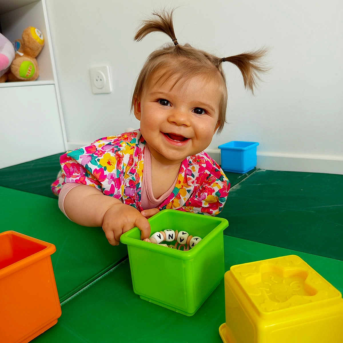 Lyana a rejoint le concours — aidez-le/la à gagner de superbes lots ! baby, child, colorful_clothing, cute, early_childhood, face, floor, fun, green_mat, happy, indoor, person, pigtails, plastic_toys, play, portrait, room, smiling, toy_blocks, young