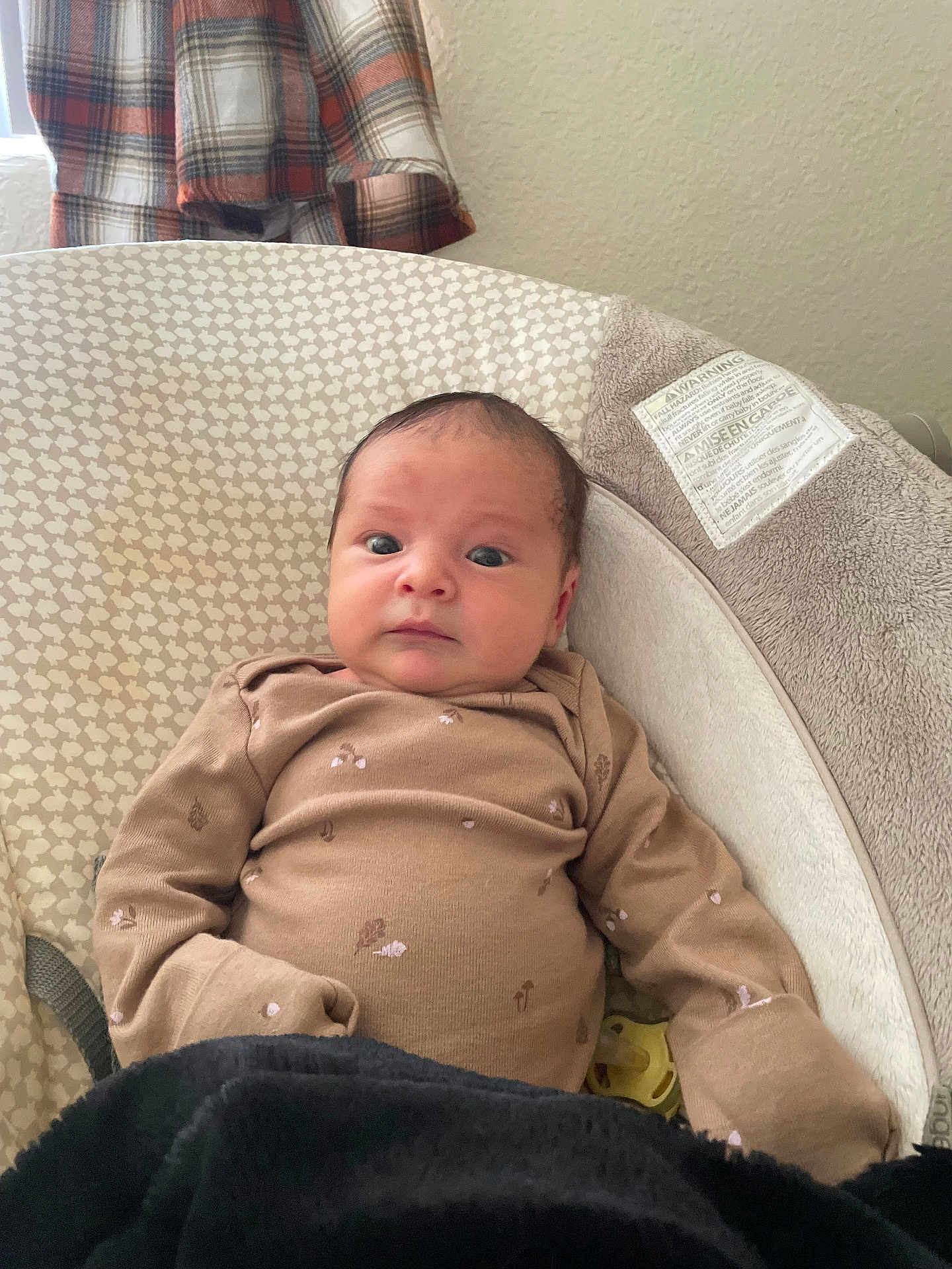 Eleanor is registered to the contest to win money with this photo: baby, infant, onesie, blanket, cushion, pattern, face, person, plaid_shirt, window, wall, indoor, clothing, pacifier, head, expression, comfort, home, soft, baby_seat