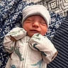 Jaxson is registered to the contest to win money with this photo: newborn, baby, sleeping, onesie, hat, dinosaur_print, blanket, patterned_blanket, cozy, infant, cute, peaceful, soft_lighting, closeup, indoor, child, portrait, resting, tiny_hands, nursery