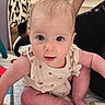 baby, infant, child, cute, blue_eyes, sitting, clothing, ladybug_pattern, quilt, furniture, person, indoor, curious, face, skin, hair, foot, hand, expression, home