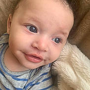 Moses is registered to the contest to win money with this photo: baby, blanket, child, closeup, curly_hair, cute, dimple, expression, eyes, face, happy, head, infant, mouth, onesie, portrait, skin, smile, soft_texture, striped_clothing