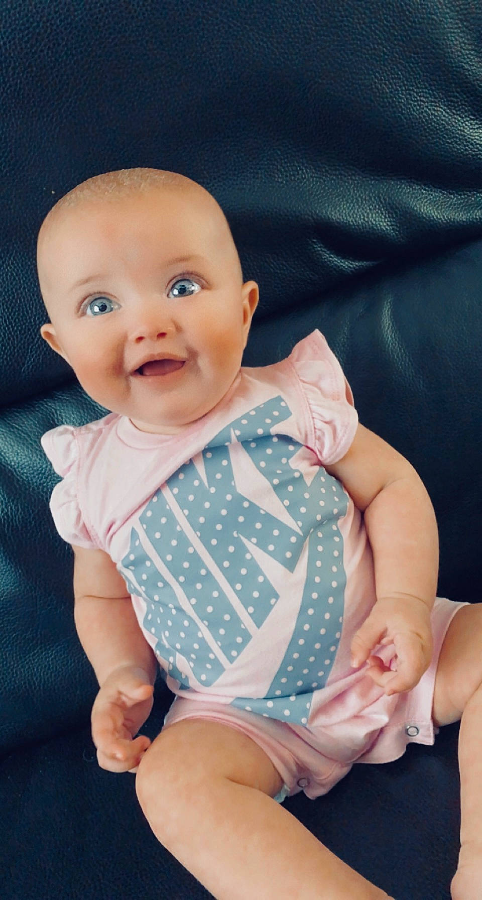 Jade participe au concours pour gagner de l'argent avec cette photo : baby, baby_toddler_clothing, cheek, collar, comfort, eye, finger, gesture, hand, happy, linens, nail, pattern, person, pink, skin, sleeve, smile, thigh, thumb