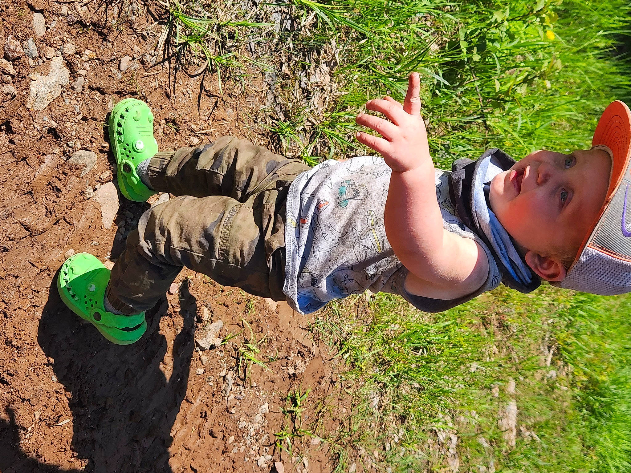 Chase is registered to the contest to win money with this photo: adventure, boot, child, elbow, fun, grass, happy, headwear, landscape, leisure, people_in_nature, person, plant, play, recreation, rock, shadow, sitting, smile, soil
