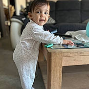 Giulia a rejoint le concours — aidez-le/la à gagner de superbes lots ! baby, child, infant, onesie, white_clothing, standing, saliva, wooden_table, living_room, sofa, curious, face, person, home_interior, floor, toy, photography, cute, portrait, furniture