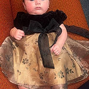 Ava joined the competition — help win amazing prizes! baby, child, infant, dress, headband, bow, couch, orange, fabric, barefoot, indoors, person, cute, portrait, fashion, sitting, young, skin, legs, hands