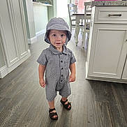 Caden joined the competition — help win amazing prizes! toddler, child, indoor, flooring, clothing, hat, footwear, sandals, cabinet, kitchen, furniture, person, smile, curious, standing, wood_floor, buttoned_shirt, bucket_hat, shorts, young_child