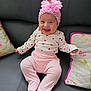 baby, infant, smiling, pink_clothing, headband, butterfly, couch, pillow, happy, child, sitting, white_shirt, heart_pattern, footed_pants, indoor, cute, portrait, young_child, comfortable, home