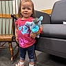 Aleigha is registered to the contest to win money with this photo: child, toddler, girl, portrait, smiling, standing, toy, stuffed_animal, plush_toy, pink_shirt, hair_bow, jeans, sneakers, socks, rocking_chair, sofa, living_room, indoor, wooden_floor, happy