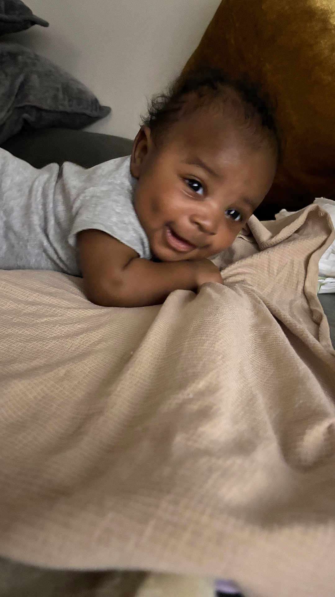 Knoah joined the competition — help win amazing prizes! baby, infant, smiling, face, blanket, cushion, indoor, child, cute, lying_down, dimples, soft_texture, cozy, person, head, curly_hair, apparel, toddler, expression, happy